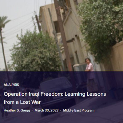 A soldier walking down a street near people in Iraq