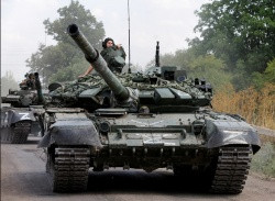 Soldiers driving two tanks down a road